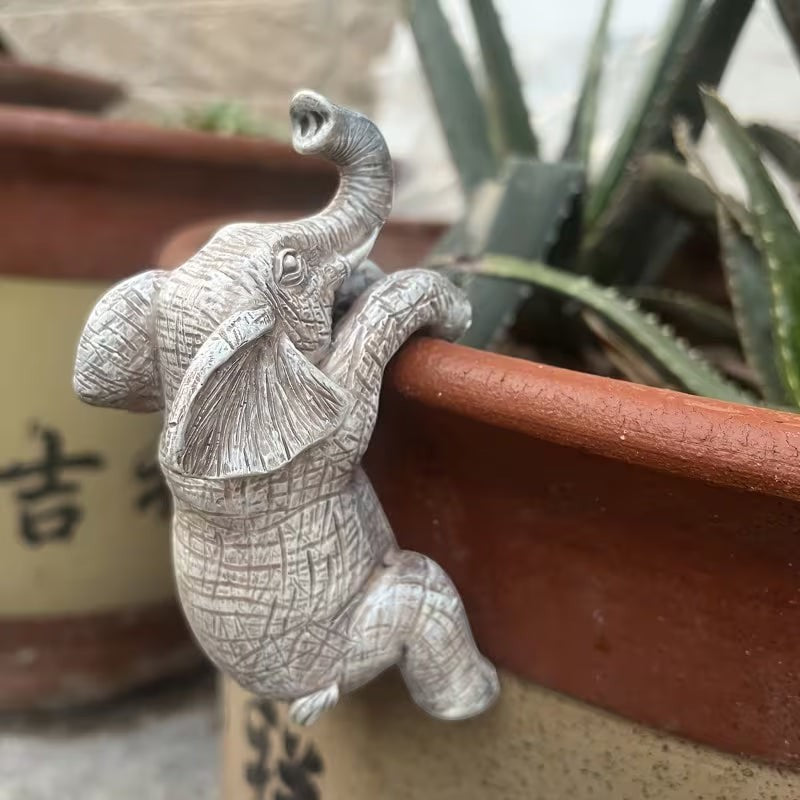 Dkor Ltd grey resin elephant pot hugger figurine with detailed texture, perched on a terracotta pot rim.