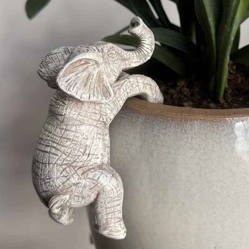 Dkor Ltd white distressed elephant pot hugger figurine climbing on a plant pot rim.